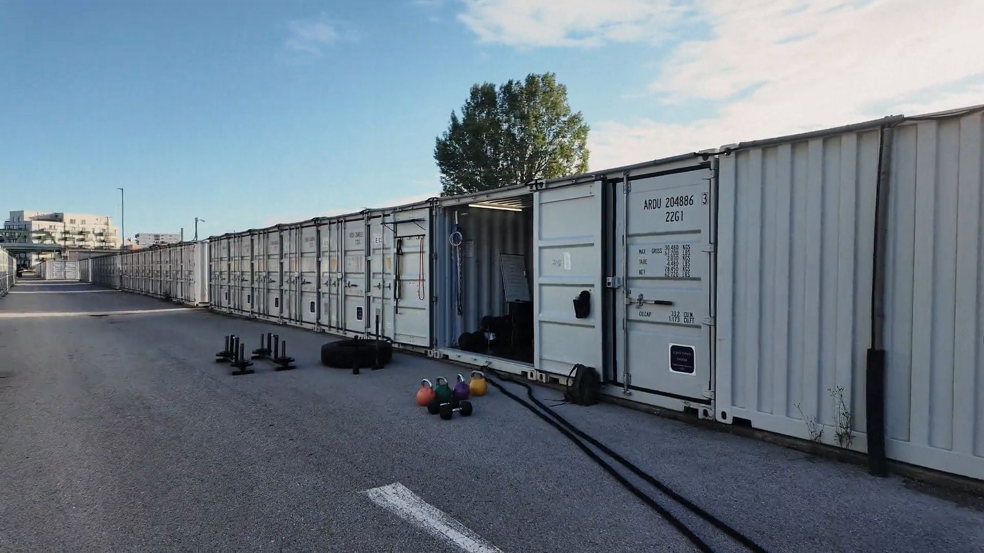 Base33 Container Gym in Wien Floridsdorf mit Kettlebells, Reifen und Schlitten vor dem offenen Container